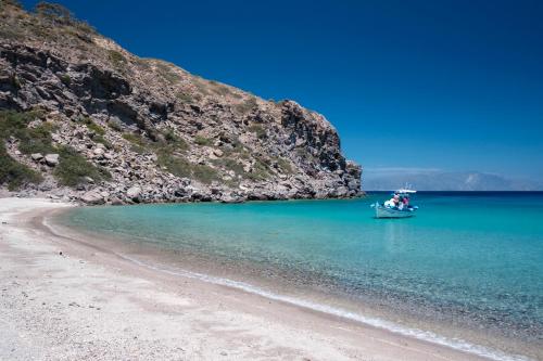 a boat in the water next to a beach at My Old Stone House in a 2 000 sqm private garden with Fab Glamping Tent in Mandrakion