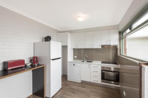 a kitchen with white cabinets and a white refrigerator at Whalevue - Unit 2 in Eden