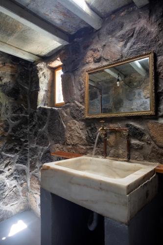 a stone bathroom with a sink and a mirror at My Old Stone House in a 2 000 sqm private garden with Fab Glamping Tent in Mandrakion