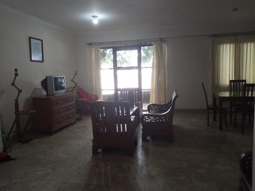 a living room with chairs and a television and a window at PENGINAPAN KONDOMINIUM CARITA - PAK BoS in Carita