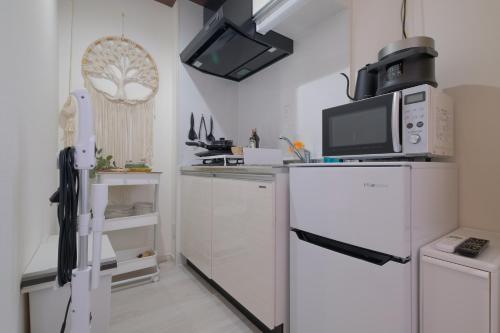 a kitchen with a white refrigerator and a microwave at Le Soleil Asato in Naha