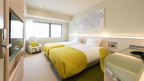 um quarto de hotel com uma cama com um cobertor amarelo em remm Roppongi em Tóquio