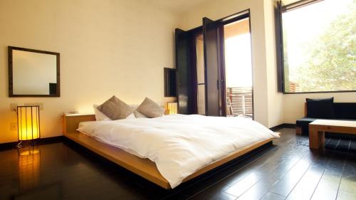 a bedroom with a large white bed and a window at Hotel Allamanda大人の隠れ家リゾート in Nara