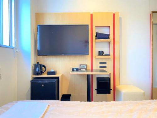 a bedroom with a flat screen tv on a wall at Center Hotel Narita2 R51 in Narita