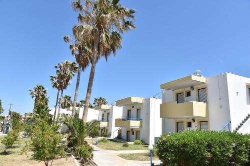 a building with palm trees in front of it at 1-Bedroom Kos Olympia Apartment at Lambi Beach in Lampi