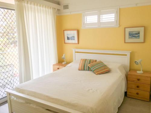a bedroom with a white bed and a window at Beachfront 4 Unit 4 of 12 Bundella Ave LC in Lake Cathie