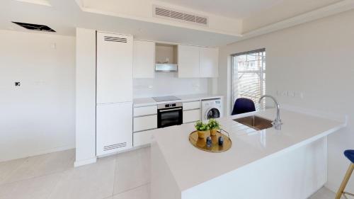 a white kitchen with a counter and a sink at Emerald Suites in Protaras