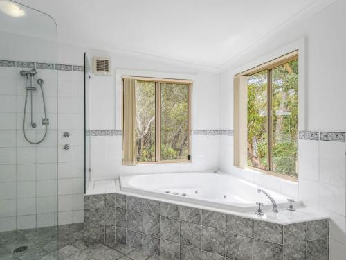 een witte badkamer met een bad en een douche bij Banksia Breeze 5 Birramal Dr Dunbogan in Dunbogan