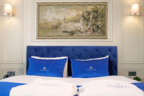 a blue bed with two blue pillows and a painting at Sarissa Hotel in Istanbul