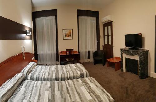a hotel room with a bed and a television at Hotel de La Paix in Oloron-Sainte-Marie