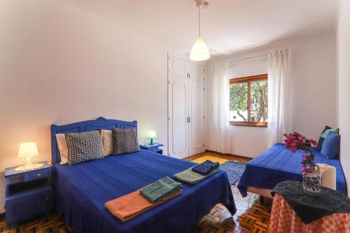 a bedroom with two beds with blue sheets and a window at Casa Tangerina in Tavira