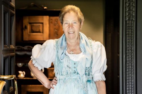 an older woman in a blue dress is smiling at BOUTIQUEHOTEL das edelweiss in Schoppernau