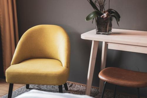 a yellow chair next to a table with a plant at BOUTIQUEHOTEL das edelweiss in Schoppernau