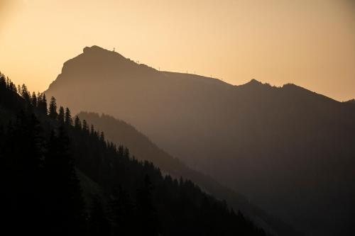 a silhouette of a mountain with trees in the foreground at BOUTIQUEHOTEL das edelweiss in Schoppernau