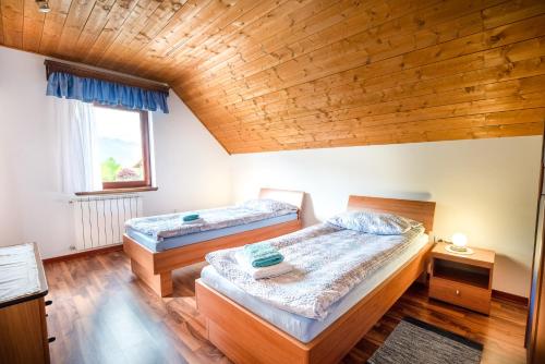 two beds in a room with a wooden ceiling at Holiday apartment Pika in Bovec