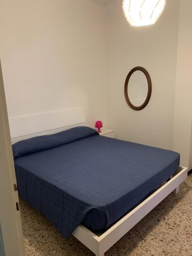 Schlafzimmer mit einem Bett mit blauer Tagesdecke und einem Spiegel in der Unterkunft Casa Bianca 6 - confortevole in centro a Moneglia in Moneglia