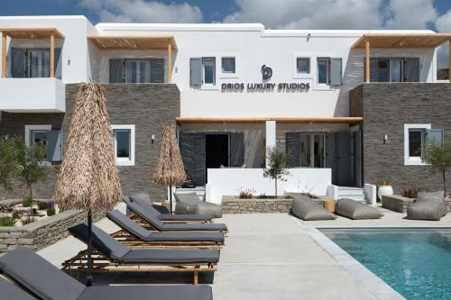 a villa with a swimming pool and lounge chairs at Drios Luxury Studios in Drios