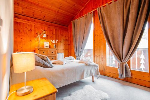 a bedroom with a bed and a large window at Chalet Perle in La Plagne Tarentaise