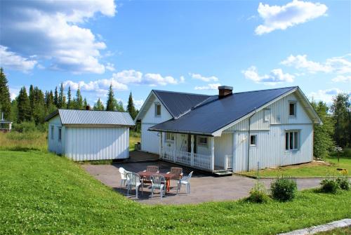 ein weißes Haus mit einem Tisch und Stühlen davor in der Unterkunft Camp Alta Kiruna in Kiruna