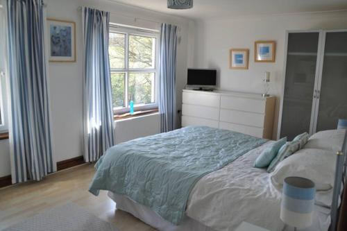 a bedroom with a bed and a television and a window at Pembroke Townhouse in Pembrokeshire