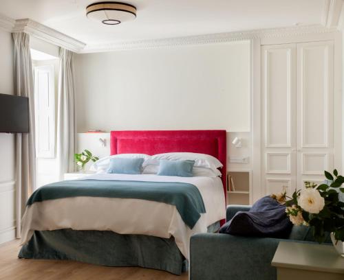 a bedroom with a large bed with a red headboard at Gran hotel Brillante in San Esteban de Pravia