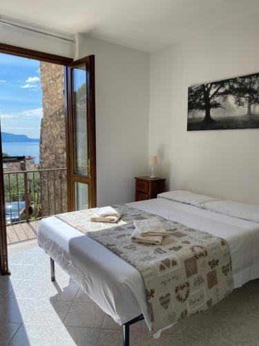 Habitación blanca con cama y balcón. en AGORA' Home, en Gardone Riviera
