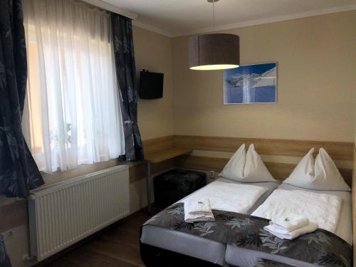 a bedroom with a bed with white sheets and a window at Hotel Mallnitz in Mallnitz