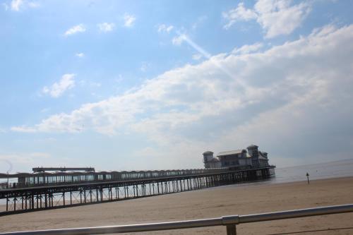 a pier on the beach with a person walking on the beach at Parasol Weston Guest House in Weston-super-Mare