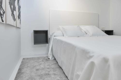 1 dormitorio blanco con 1 cama blanca y TV en ANDALUCIA Modern y Luxury, en Sevilla