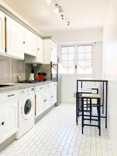 - une cuisine blanche avec un lave-linge et une table dans l'établissement Résidence Le Castille, à Nice