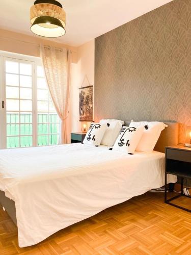 une chambre avec un grand lit blanc et une fenêtre dans l'établissement Résidence Le Castille, à Nice