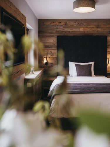 a bedroom with a bed with a wooden wall at VAYA Post Saalbach inklusive Joker Card in Saalbach Hinterglemm