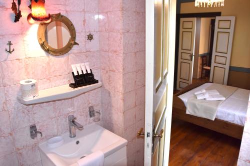 a bathroom with a sink and a room with a bed at Aeginitikon Arhontikon Stylish Boutique Hotel in Egina