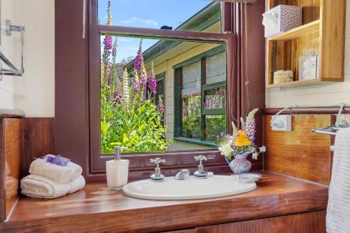 baño con lavabo y ventana con flores en Hamlet Downs Country Accommodation en Fentonbury