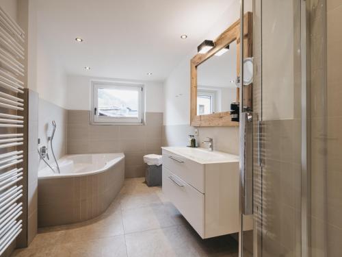 a bathroom with a bath tub and a sink and a bath tub at VAYA Post Saalbach inklusive Joker Card in Saalbach Hinterglemm