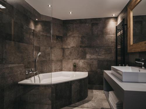 a bathroom with a tub and a sink at VAYA Post Saalbach inklusive Joker Card in Saalbach Hinterglemm