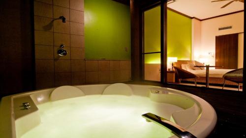 a bath tub in a room with a bedroom at Hotel Allamanda大人の隠れ家リゾート in Nara