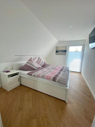 a white bedroom with a bed and a window at Ferienwohnung Dörrwies in Sankt Wendel