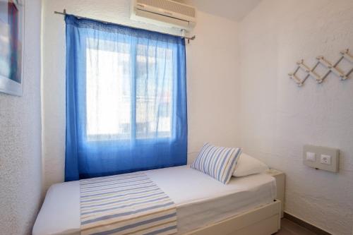 a bed with a blue curtain and a window at Blue Senses Apartments in Sarti