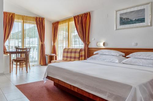 um quarto com uma cama grande, uma mesa e cadeiras em Hotel Posejdon em Neum