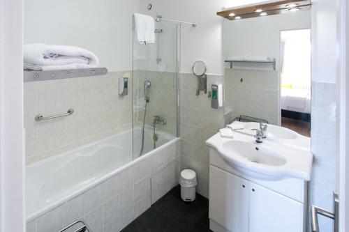 a white bathroom with a sink and a shower at Le Cotentin Appart'hôtels & Restaurant le Cot' in Portbail