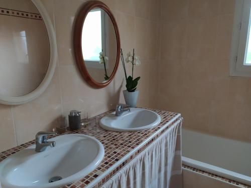 een badkamer met 2 wastafels, een spiegel en een bad bij Villa Maryne in Andernos-les-Bains
