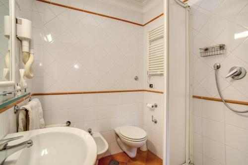 a white bathroom with a toilet and a sink at PRIMAVERA GH in Rome