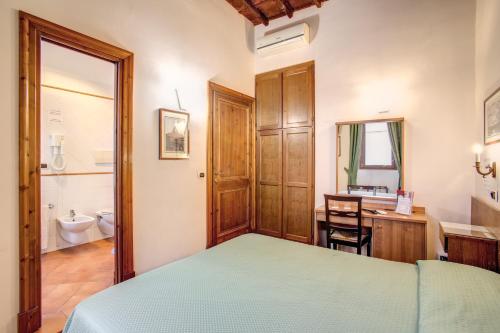 a bedroom with a bed and a desk and a bathroom at PRIMAVERA GH in Rome