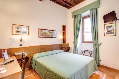 Schlafzimmer mit einem Bett, einem Schreibtisch und einem Fenster in der Unterkunft PRIMAVERA GH in Rom
