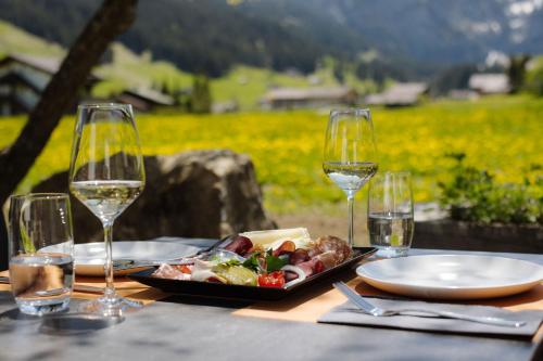 a table with a plate of food and glasses of wine at Bodehüttli in Adelboden