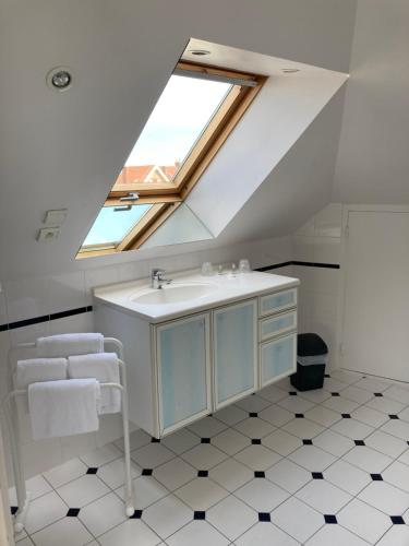 ein Badezimmer mit einem Waschbecken und einem Dachfenster in der Unterkunft Hôtel de la Mer in Pléneuf-Val-André