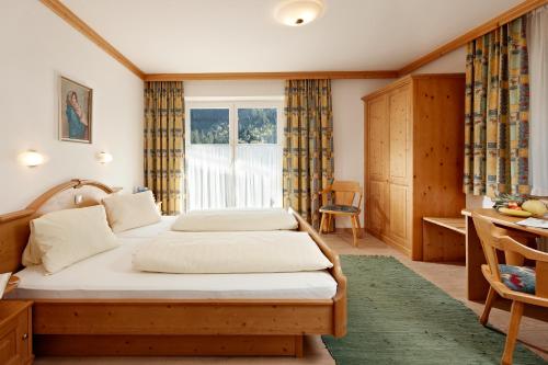 a bedroom with two beds and a desk and a window at Gästehaus Edelweiss in Krimml