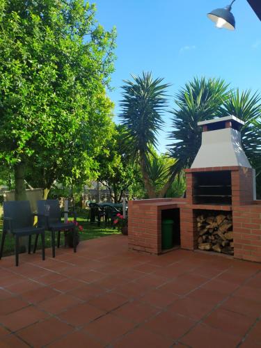 a brick fireplace on a patio with chairs and trees at Casa da Nanda in Crespos