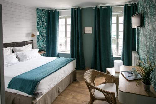 a bedroom with a bed with green curtains and a desk at Le Cotentin Appart'hôtels & Restaurant le Cot' in Portbail
